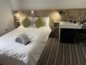 Une chambre d’hôtel équipée d’un lit, d’une table de chevet, d’un bureau et d’une machine à café.