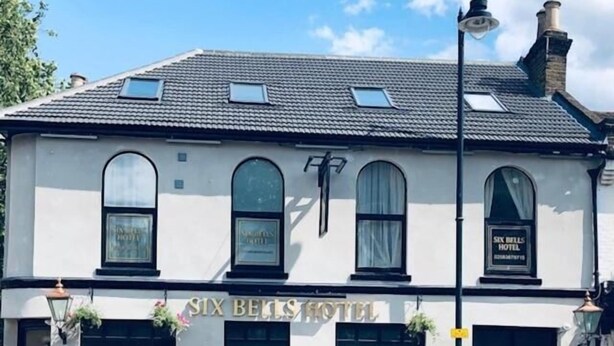 A two-story building with a sign reading "Six Bells Hotel" and a sign below stating "Live Beer Garden". - Six Bells Hotels (Enfield)