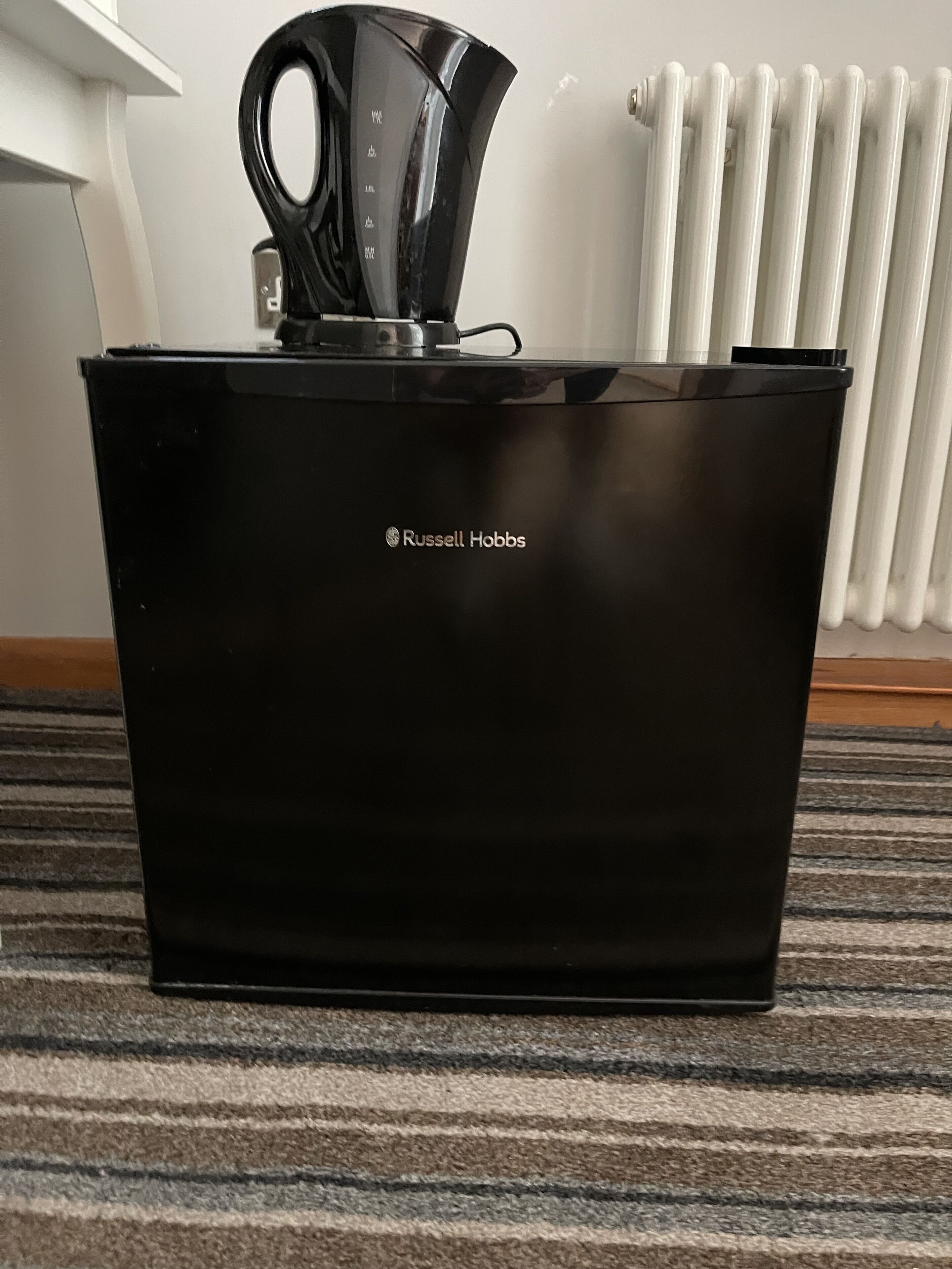 Ein schwarzes Russell Hobbs Gerät auf einem Teppichboden.