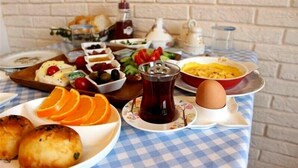 Ein Esstisch mit verschiedenen Speisen, darunter Brot, Obst und eine Tasse Tee.