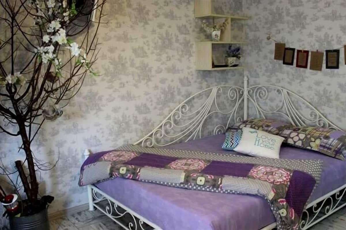 Un dormitori amb un llit, un arbre decoratiu i una paret amb quadres.