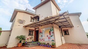 A two-story building with a covered entrance and a colorful mural. - Mahinder Inn By Sapphire Stays (Mahabaleshwar)