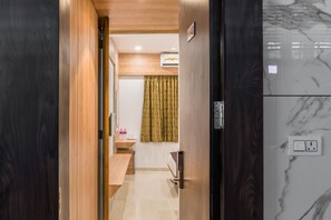 A hallway with wooden walls, a marble wall with an air conditioning unit, and a counter with bottles. - Meridian Hotel & Banquet (Surat)