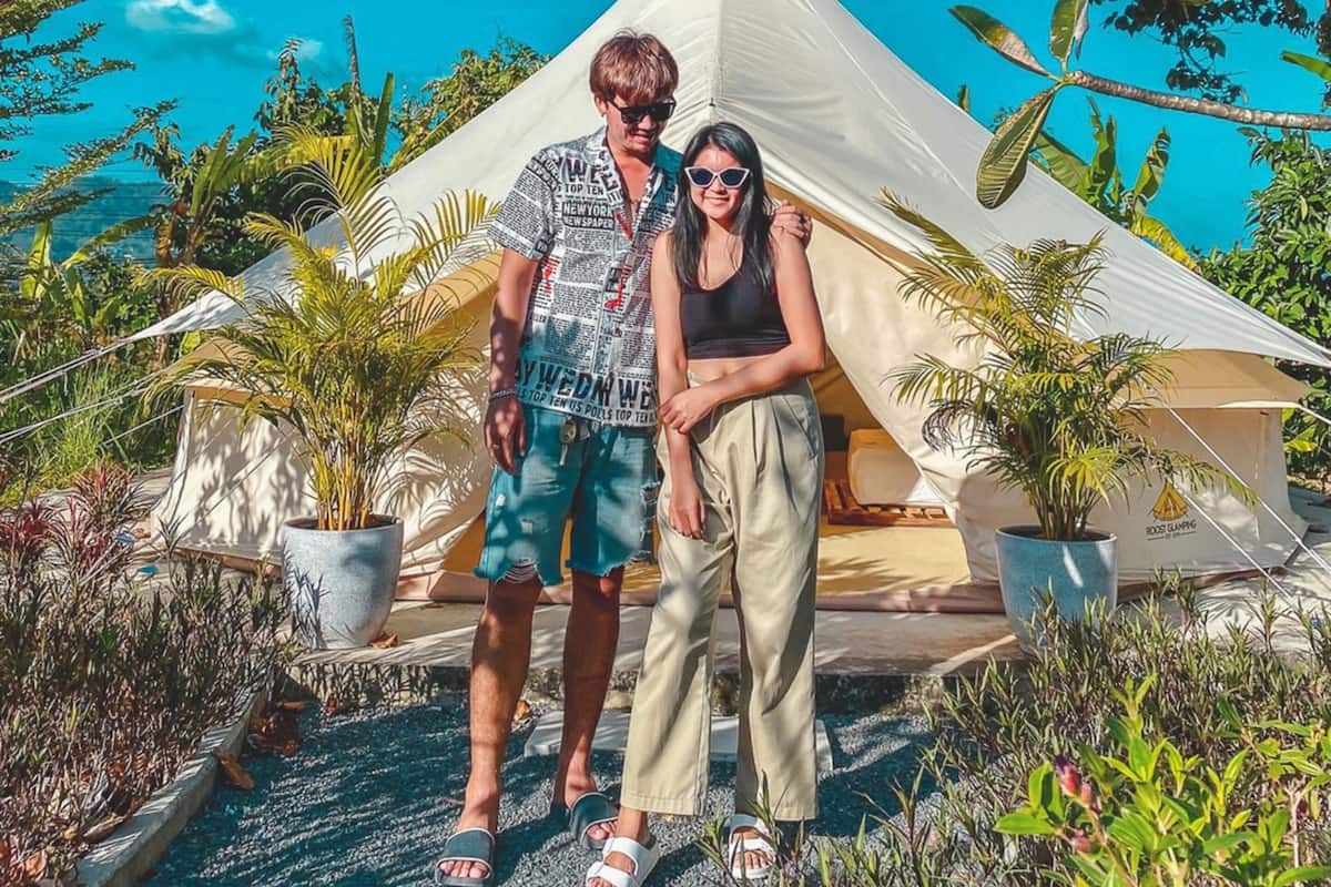 Two people standing in front of a tent with a clear blue sky in the background.