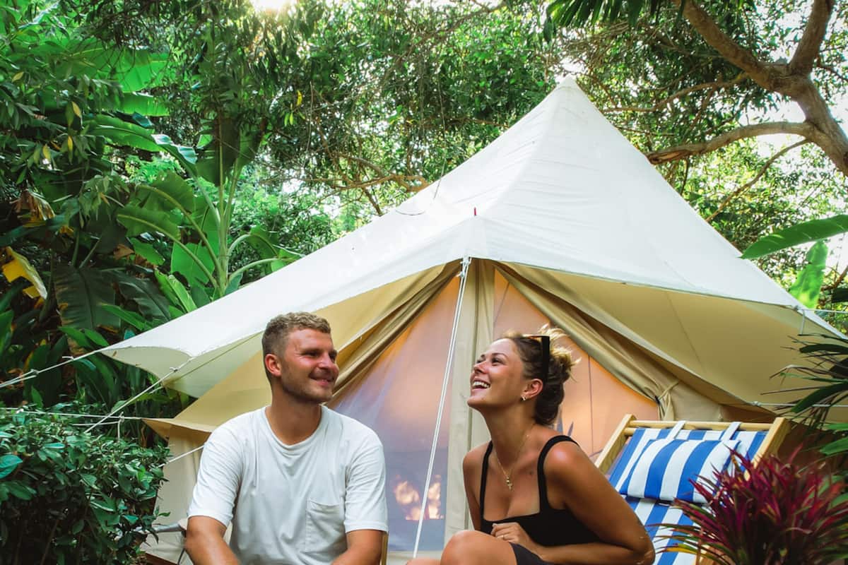 A tent with a simple design, surrounded by lush greenery.