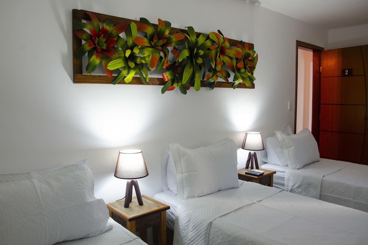 A hotel room with two beds, white bedding, and a large floral artwork on the wall.