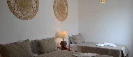 A hotel room with two beds, a bedside table with a lamp, and two woven wall decorations.