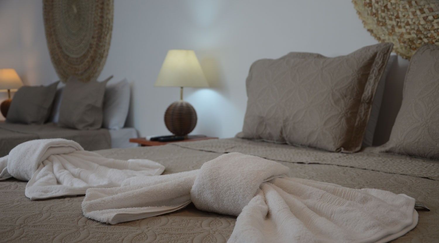 A neatly made bed with white towels, a lamp, and patterned pillows in a hotel room.