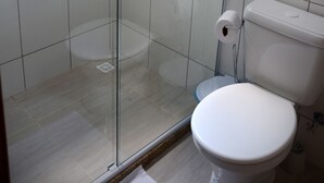 Un baño con cabina de ducha de vidrio, inodoro y perchero para toallas.
