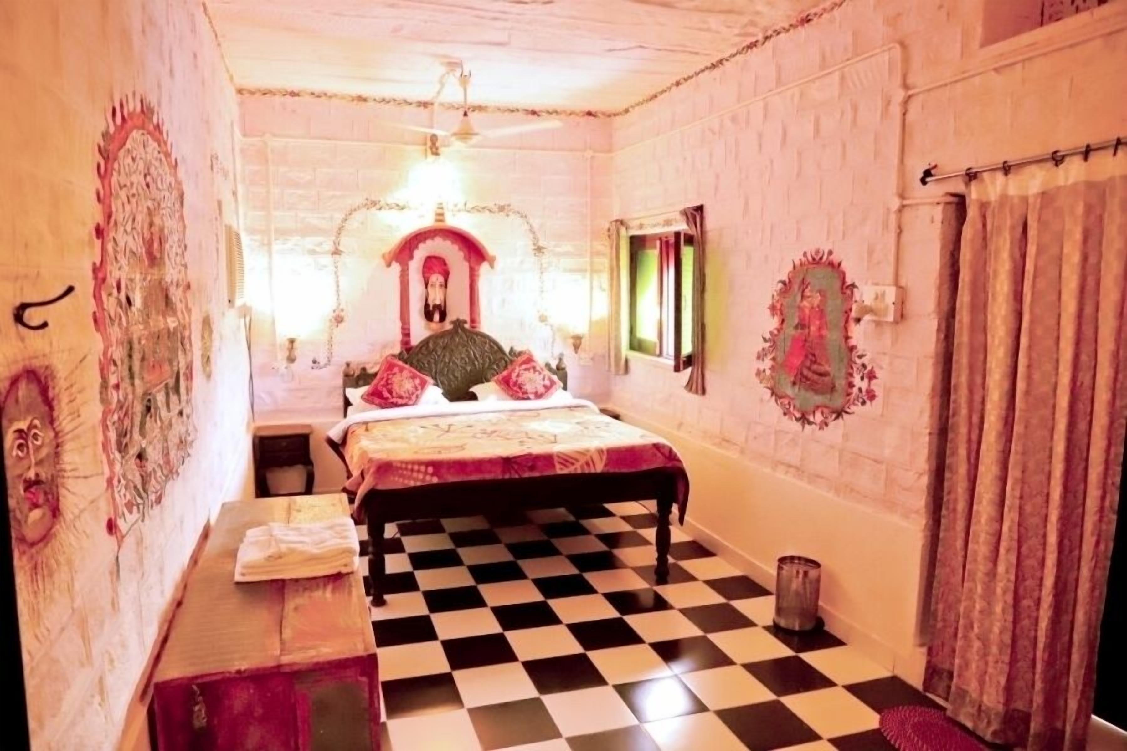 A room with a checkered floor, a bed with a decorative headboard, and a wall with a mirror and artwork.