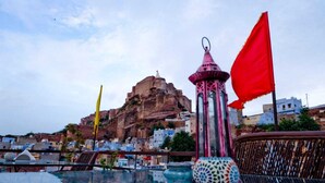 A terrace with a view of a historic building, a lantern, and a flag. - Singhvi's Haveli (Jodhpur)