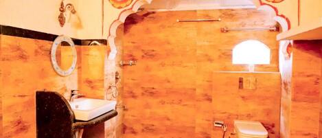 A bathroom with a wooden vanity, a sink, a mirror, a toilet, and decorative wall patterns.