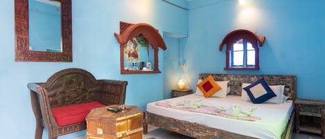 A bedroom with a bed, a wooden chair, a small table, and a mirror.