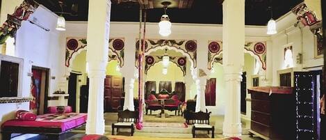 A traditional room with a bed, chairs, and a mirror.