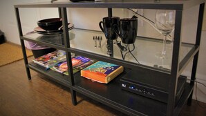 A glass-top coffee table with a remote control, a bowl, a wine glass, and a book. - New Studio  - Minutes to Convention Center, Disney,Universal ,INTL DR (Orlando)