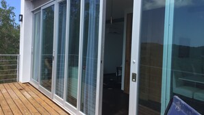 Ein modernes Gebäude mit großen Glasschiebetüren, einer Holzdachterrasse und einem einsehbaren Innenraum mit Deckenventilator.