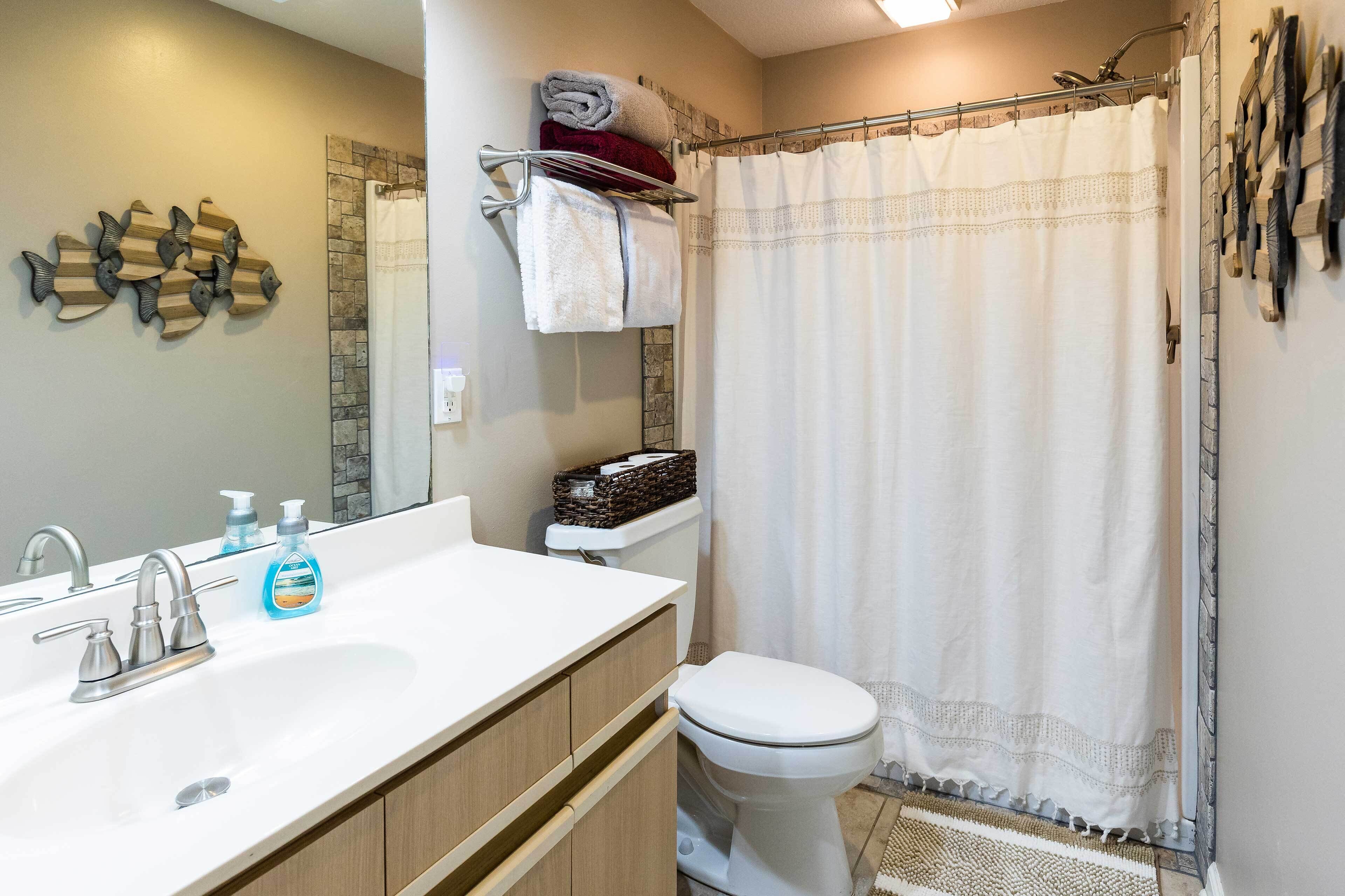 A bathroom with a white sink, a mirror, a toilet, and a shower curtain.