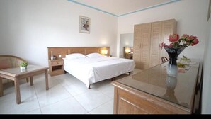 A hotel room with a bed, bedside tables, a desk, a chair, a wardrobe, and a vase with flowers. -  Hôtel Azur Conakry (Conakry)
