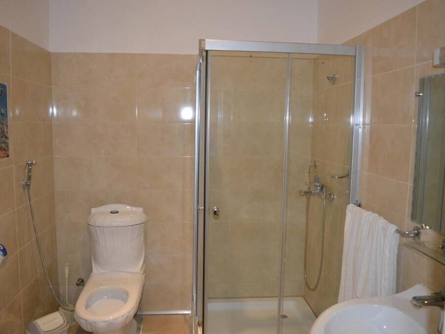 A bathroom with a toilet, a glass-enclosed shower, and a sink.