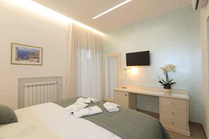 A hotel room with a bed, a bedside table with a lamp, a mirror, and a small plant. - Relais Ohana (Vico Equense)