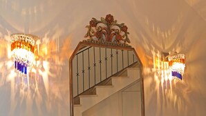 A wall-mounted mirror with an ornate frame, a staircase, and two wall sconces with decorative lamps. - Relais Ohana (Vico Equense)