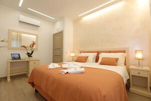 Una habitación de hotel con una cama grande, lámparas de noche, un escritorio con una computadora portátil y un espejo.