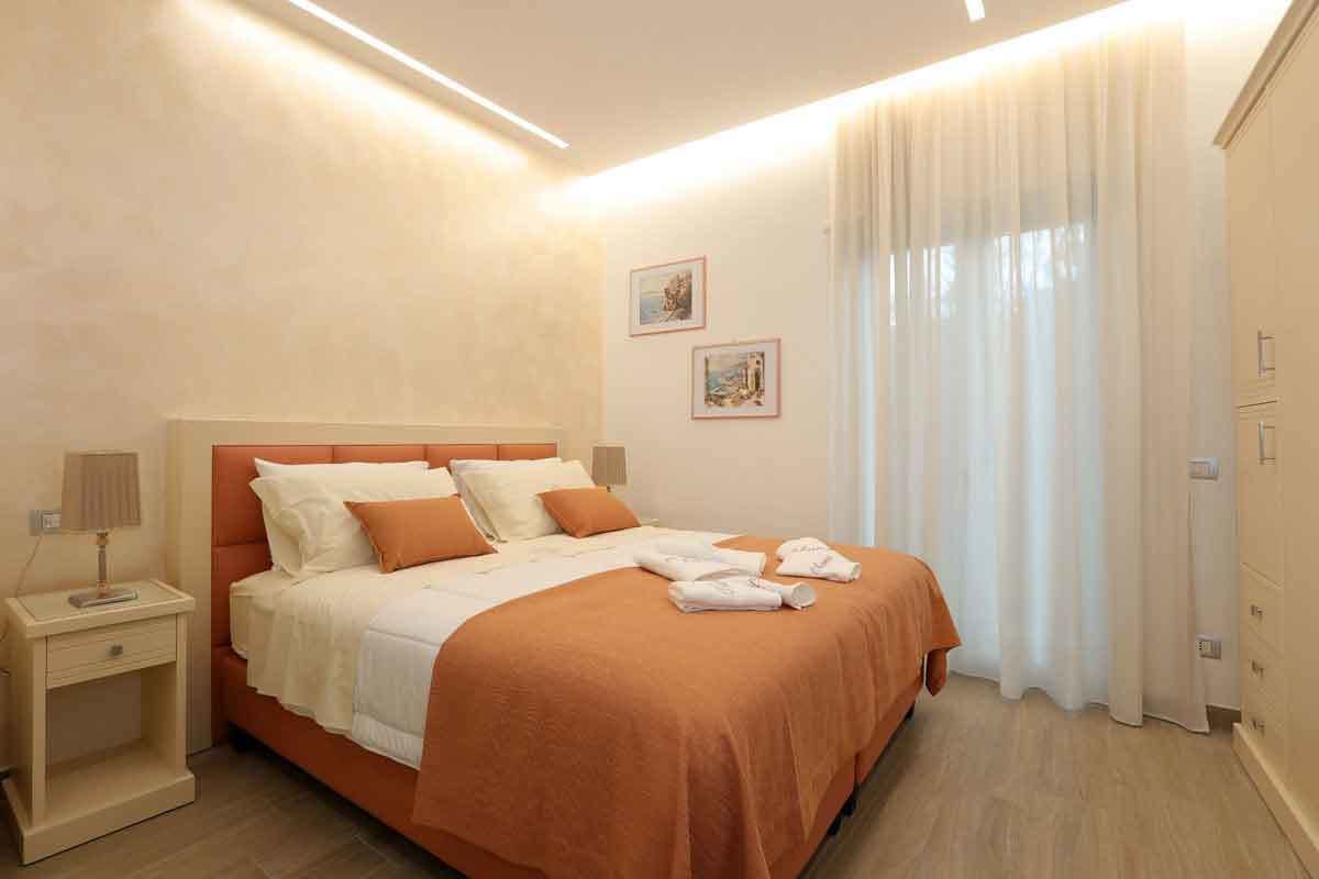 A bedroom with a bed, nightstand, and a window with curtains.