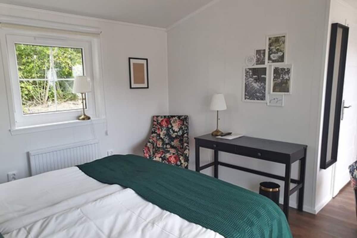 A bedroom with a bed, a desk, a chair, and a window.