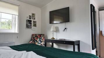 Un dormitorio con cama, escritorio, silla, televisor y ventana.