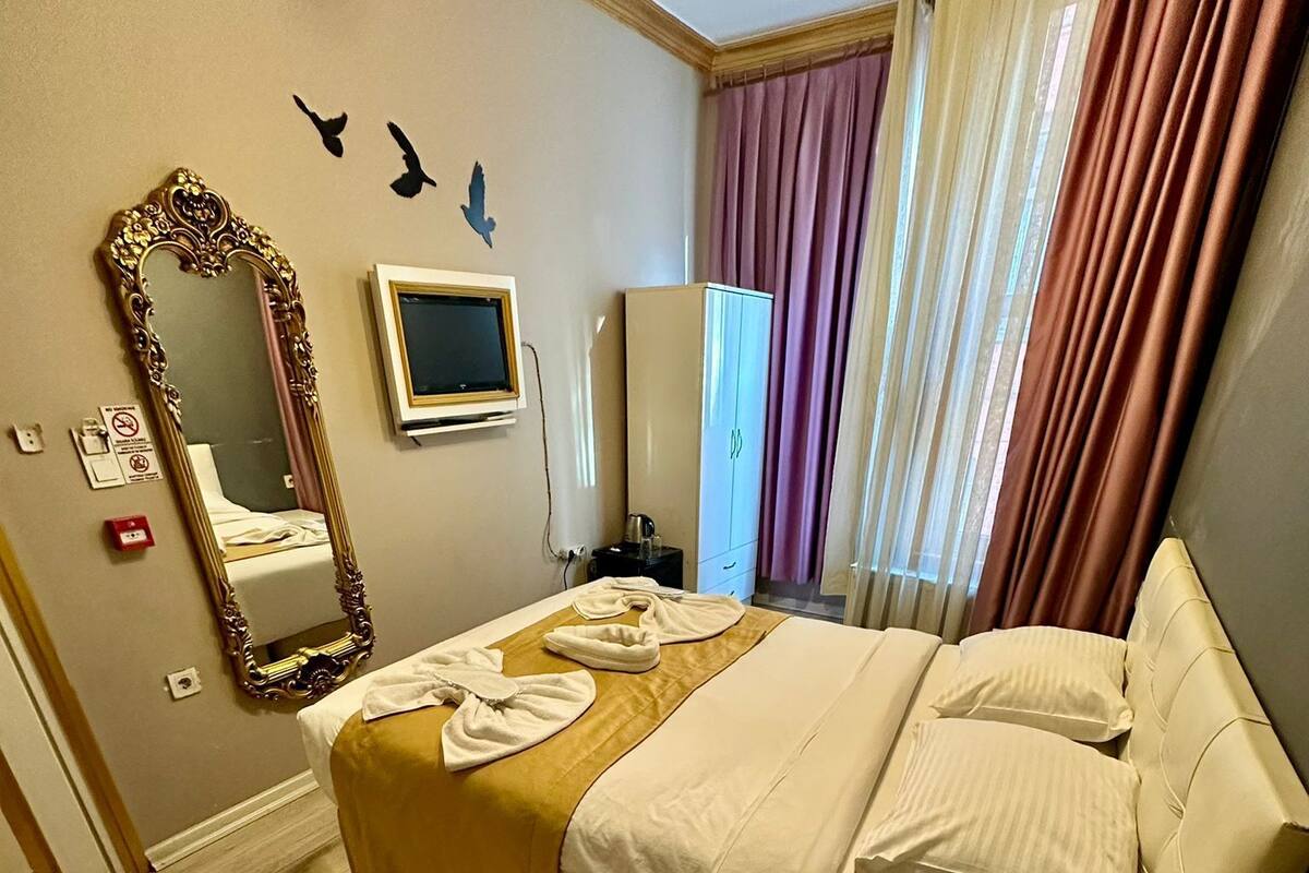 A hotel room with a bed, a bedside table, a mirror, a wardrobe, and a television.