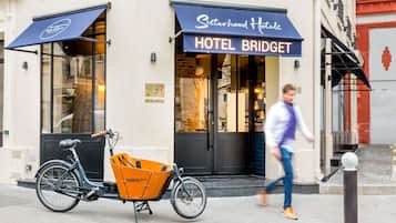 Un hotel llamado 'Hotel Bridget' con una entrada visible, una bicicleta con una caja de reparto y un peatón caminando.