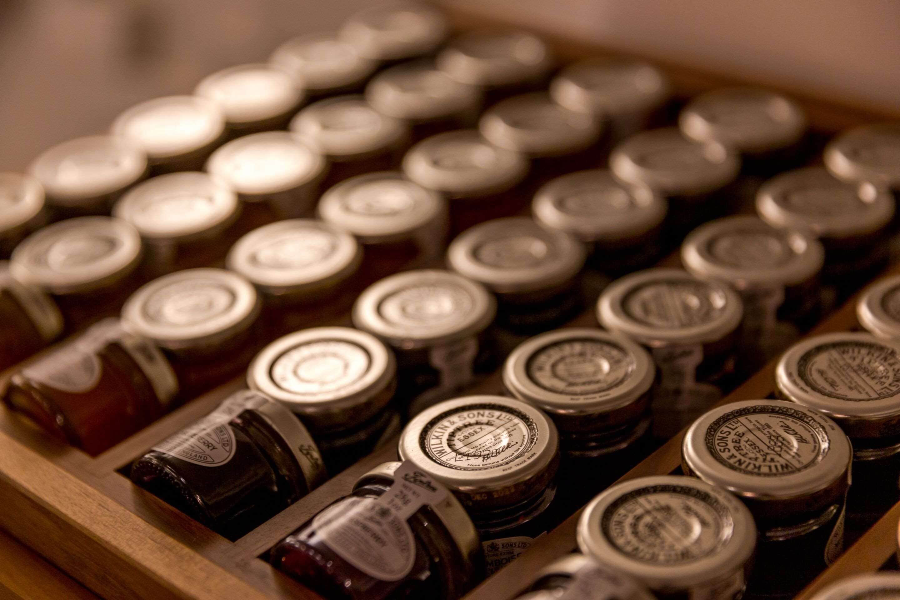 A wooden tray with multiple jars of preserves.