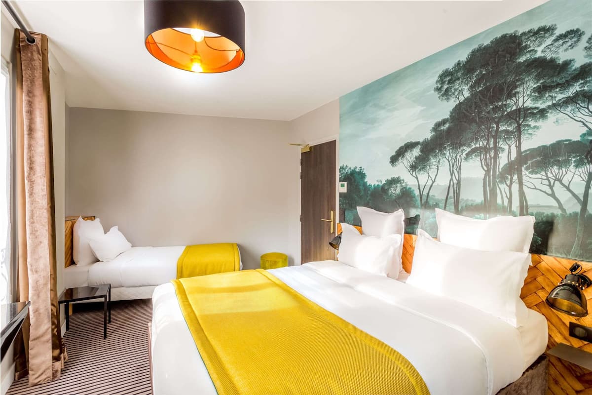 A hotel room with a large bed, a smaller bed, a painting of trees, a lamp, and a window with curtains.