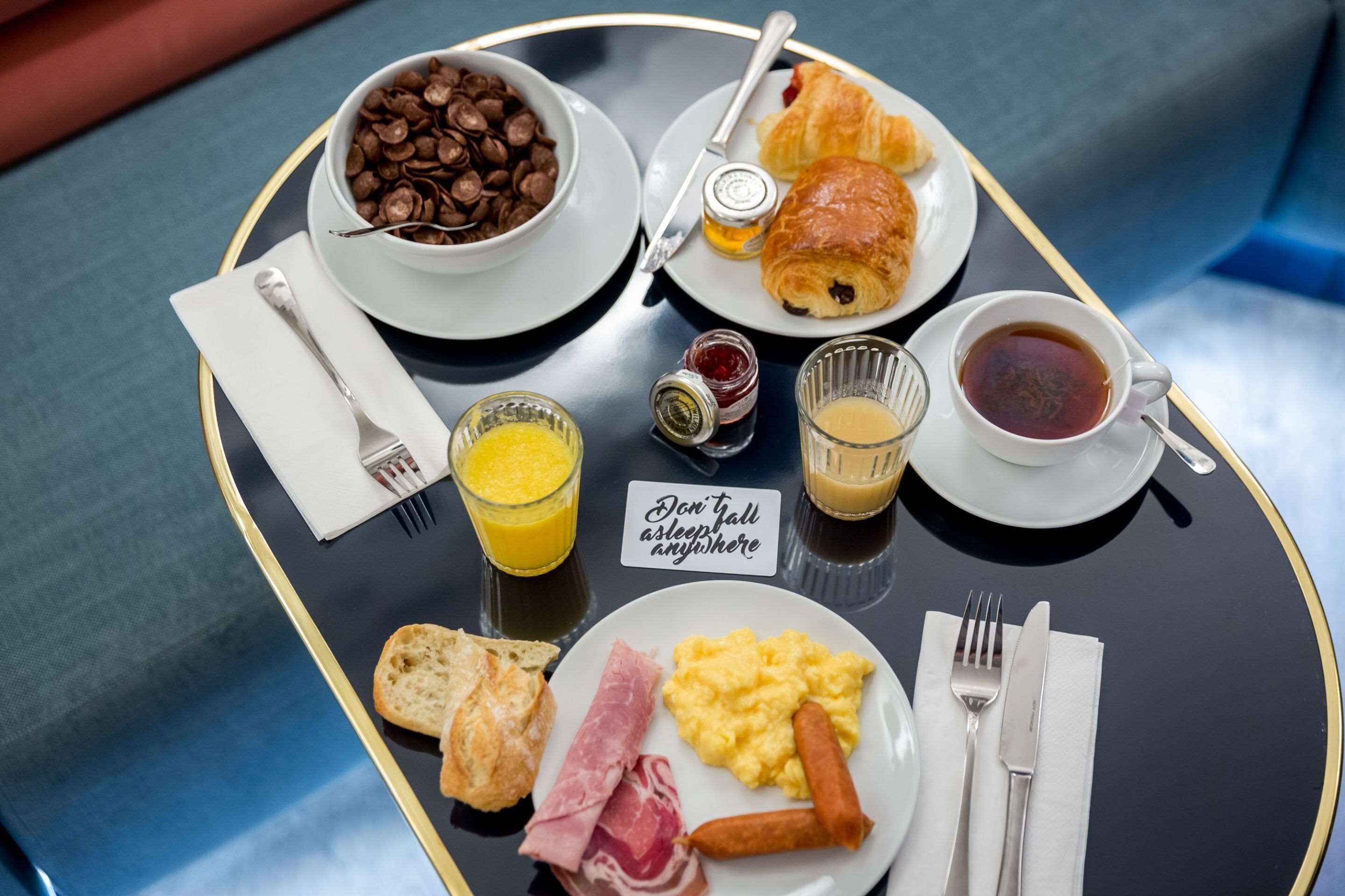 Una bandeja de desayuno con cruasanes, chips de chocolate, huevos revueltos, salchichas y tostadas.