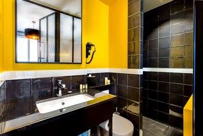 A modern bathroom with a black sink, yellow walls, and a large mirror.