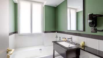 Een moderne badkamer met een badkuip, een wastafelmeubel en een haardroger bevestigd aan de muur.