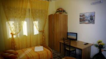 Una stanza con un letto, una scrivania, una sedia, una televisione e un quadro appeso al muro.