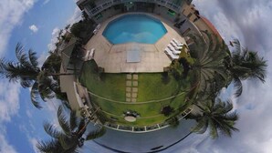 A circular view of a building with a swimming pool, surrounded by palm trees and a clear sky. - Xingu Praia Hotel (Altamira)