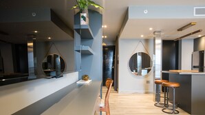 Una cocina moderna con una isla central, taburetes de bar y un espejo colgante.