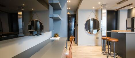 A modern kitchen with a central island, bar stools, and a hanging mirror.