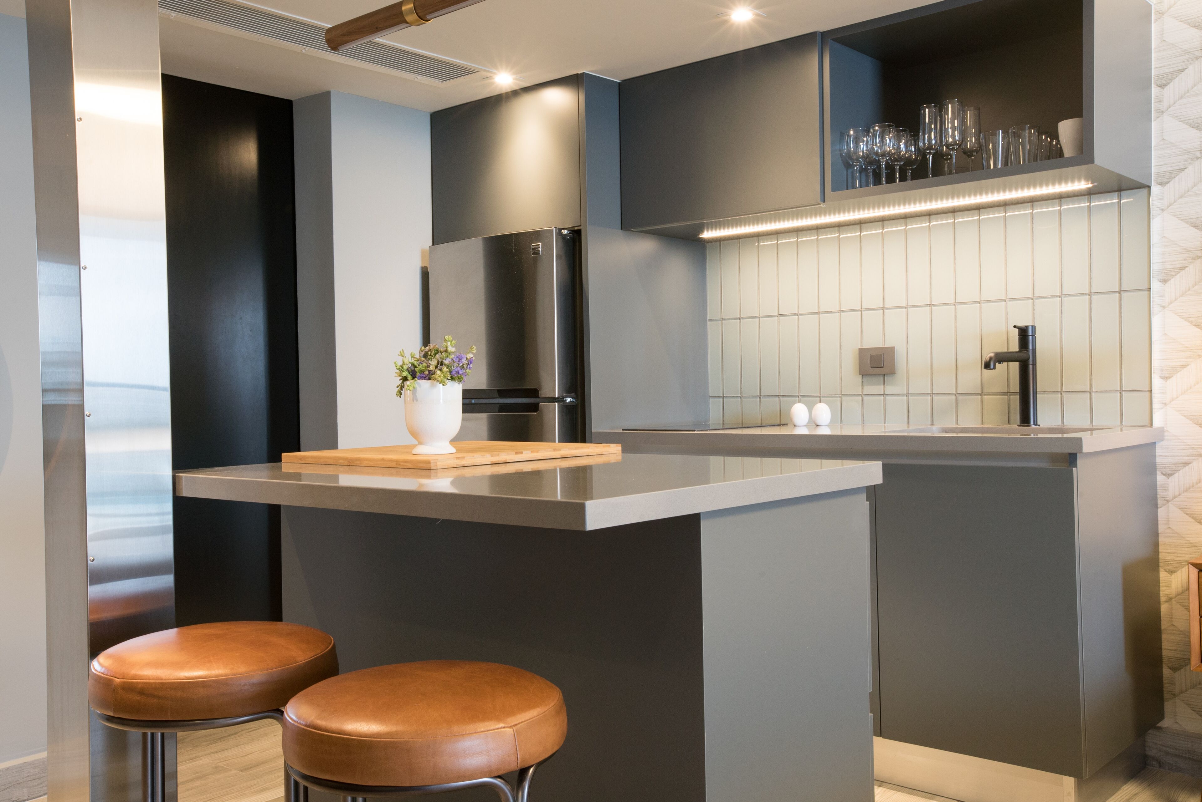 Una cucina moderna con isola centrale, elettrodomestici in acciaio inossidabile e sgabelli da bar.