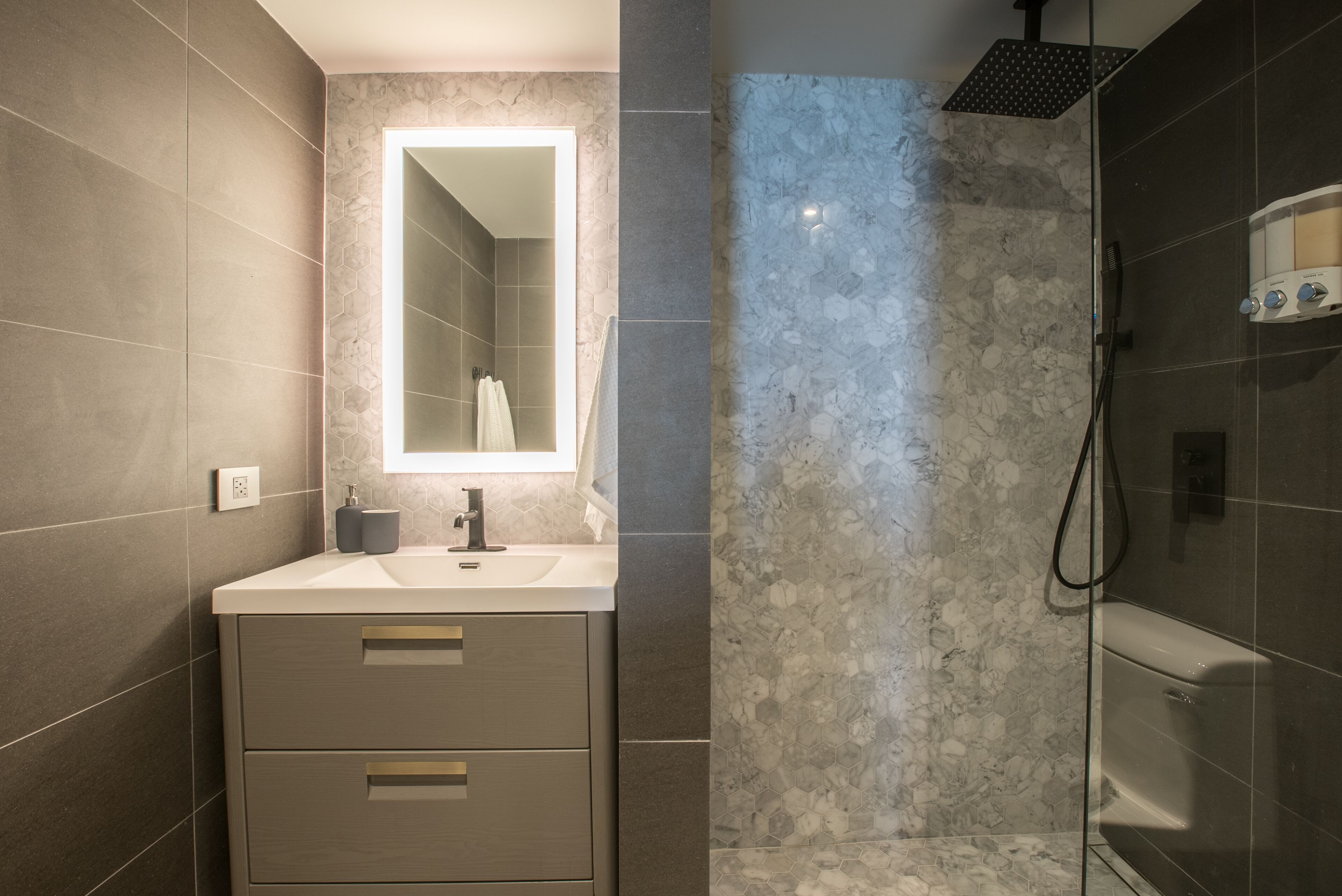 Une salle de bain moderne avec une douche en marbre, un lavabo avec un miroir et des toilettes.