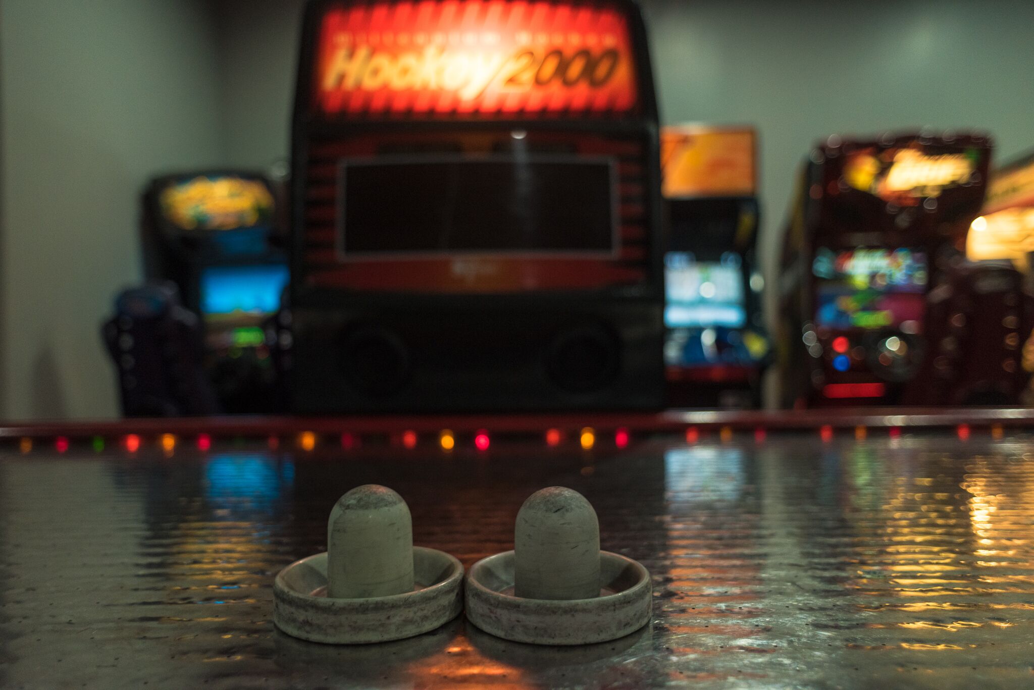 A row of arcade machines with a neon sign in the background.