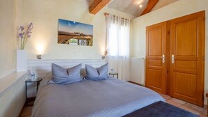 A bedroom with a bed, a nightstand, a wall-mounted picture, a window with curtains, and a wooden door. - L'Orée du Bois Bourgogne - Adults Only (Saint-Nicolas-lès-Cîteaux)