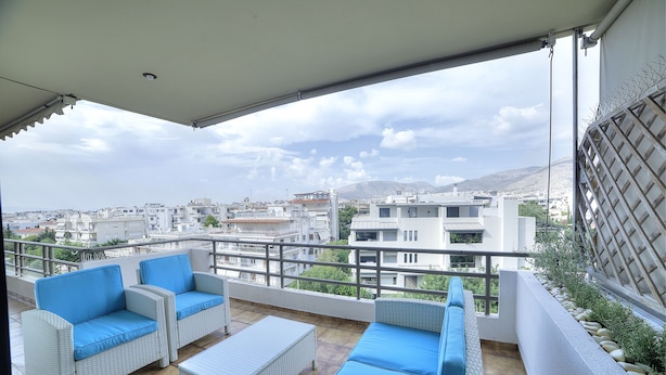 A balcony with wicker furniture and a view of the cityscape. - Athens Glyfada Riviera Apartment (Glyfada)