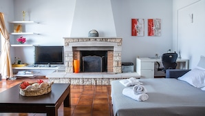 A hotel room with a fireplace, a bed, a desk, and a television. - Athens Glyfada Riviera Apartment (Glyfada)