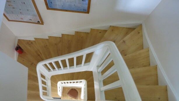 Una escalera de caracol con escalones de madera y barandillas blancas.