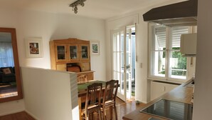 Una cocina con armarios de madera, una mesa de comedor con sillas y un ventanal grande.