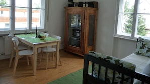 Una habitación con una mesa de madera, sillas, un armario y una cama.