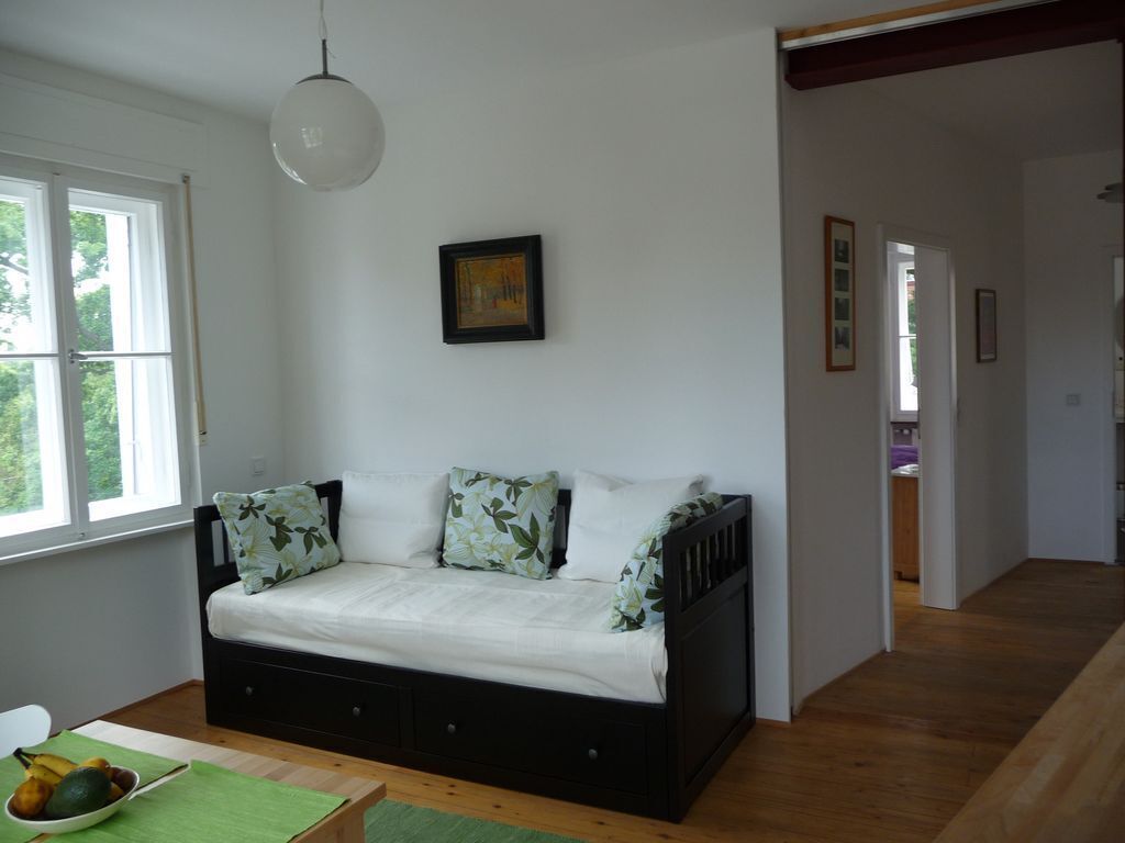 Una habitación con una cama, un tapete verde, un cuenco de fruta y un cuadro en la pared.